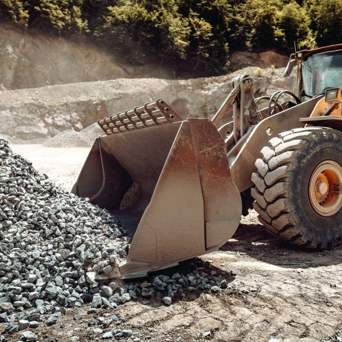 Industrial - machinery working. Close up of wheel loader loading gravel into dumper trucks