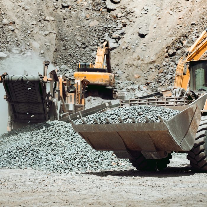 Large wheel loader on construction site transporting and loading gravel into dumper trucks Large wheel loader on construction site transporting and loading gravel into dumper trucks